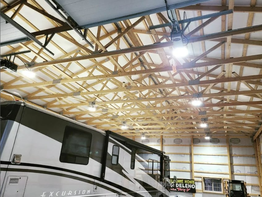Bright ceiling lights across the trusses of a large garage