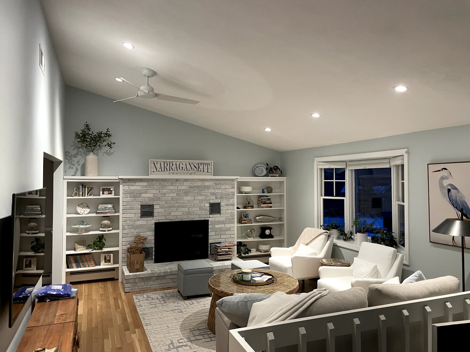A living room lit by new recessed lights, with a Narragansett sign over the fireplace